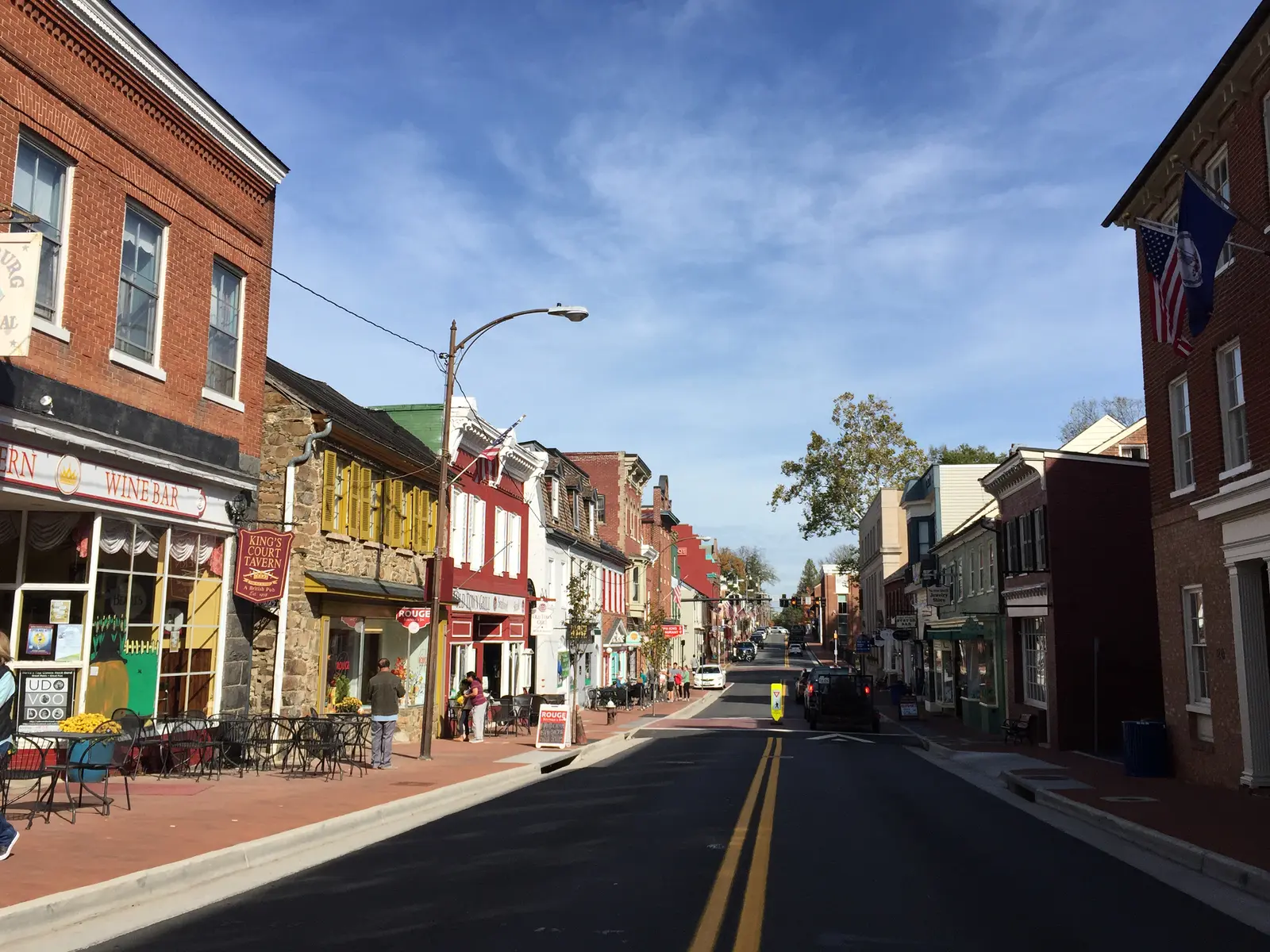 Brick and painted storefronts with cafe tables along King Street in Leesburg